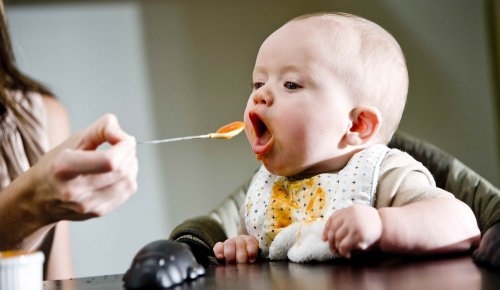 オレンジ色のピューレを食べる赤ちゃん