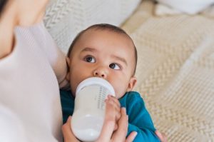 目を開けてミルクを飲む赤ちゃん