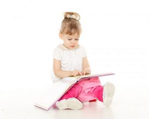本を見ながらおまるに座る女の子