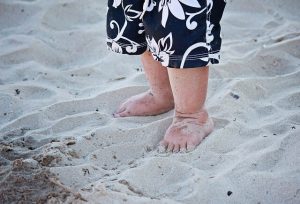 砂の上を裸足で歩く幼児