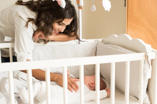 ベビーベッドに寝る赤ちゃんを見守る母親